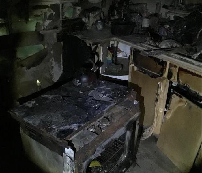 Kitchen cabinets melted by fire, soot covers the counter tops and kitchen floor.